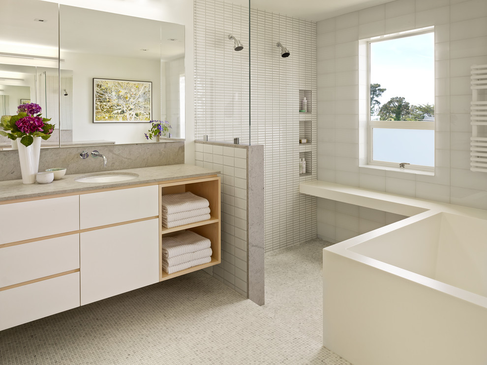 Inspiration for a contemporary master bathroom in San Francisco with an undermount sink, flat-panel cabinets, white cabinets, a freestanding tub, white tile, white walls, mosaic tile floors, a curbless shower and grey benchtops.
