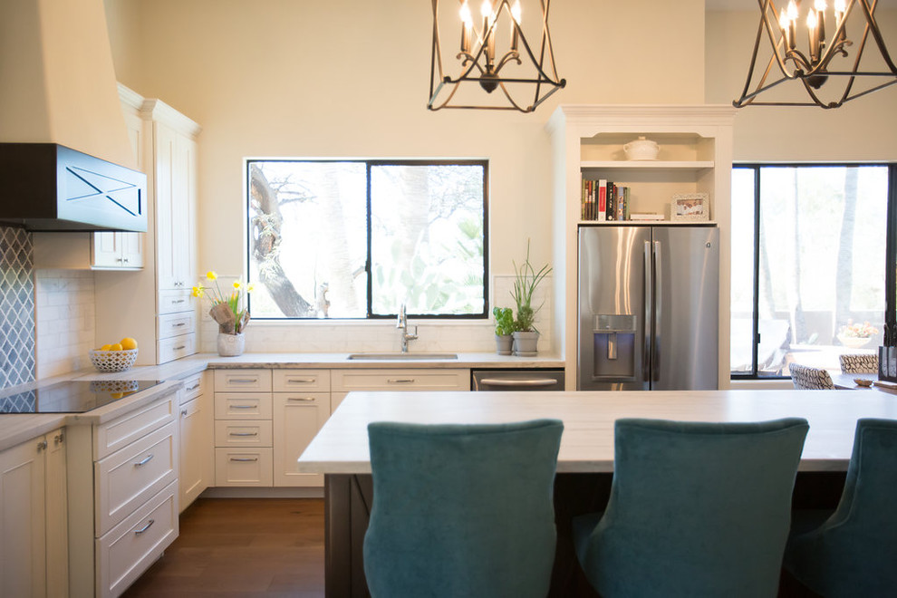 Inspiration for a large transitional l-shaped medium tone wood floor open concept kitchen remodel in Phoenix with an undermount sink, shaker cabinets, white cabinets, quartzite countertops, marble backsplash, stainless steel appliances and an island