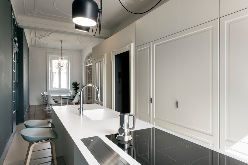 This is an example of a mid-sized contemporary single-wall open plan kitchen in Milan with an integrated sink, recessed-panel cabinets, white cabinets, quartz benchtops, stainless steel appliances, concrete floors and with island.