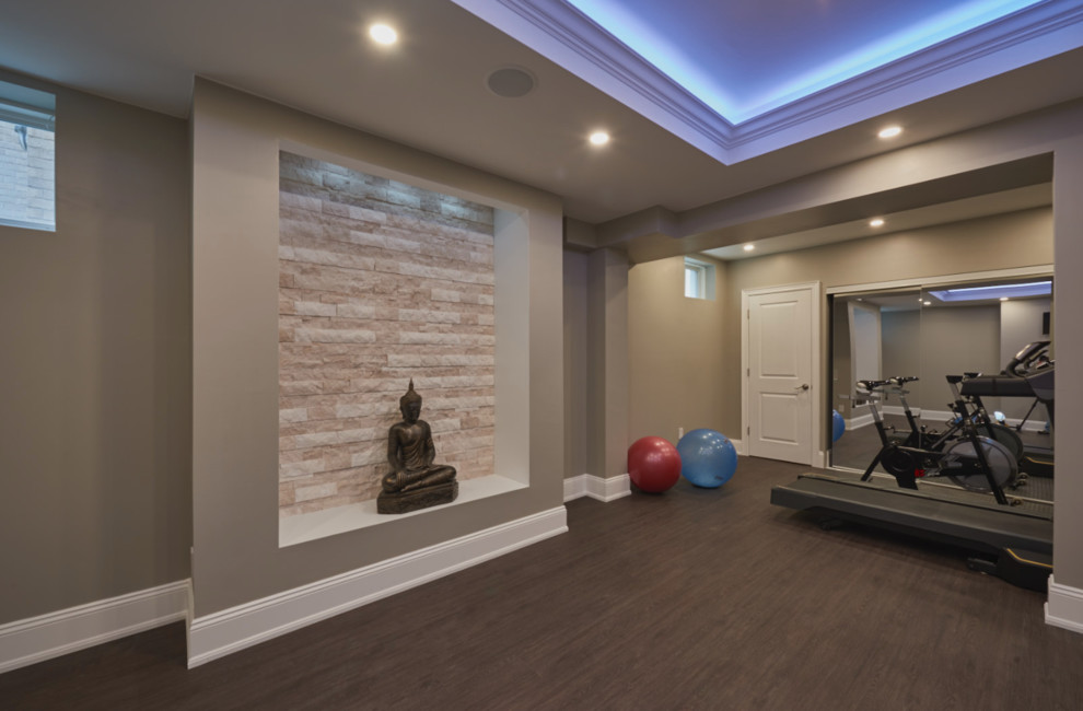 This is an example of a traditional walk-out basement in Toronto with grey walls, light hardwood floors, a ribbon fireplace and a stone fireplace surround.