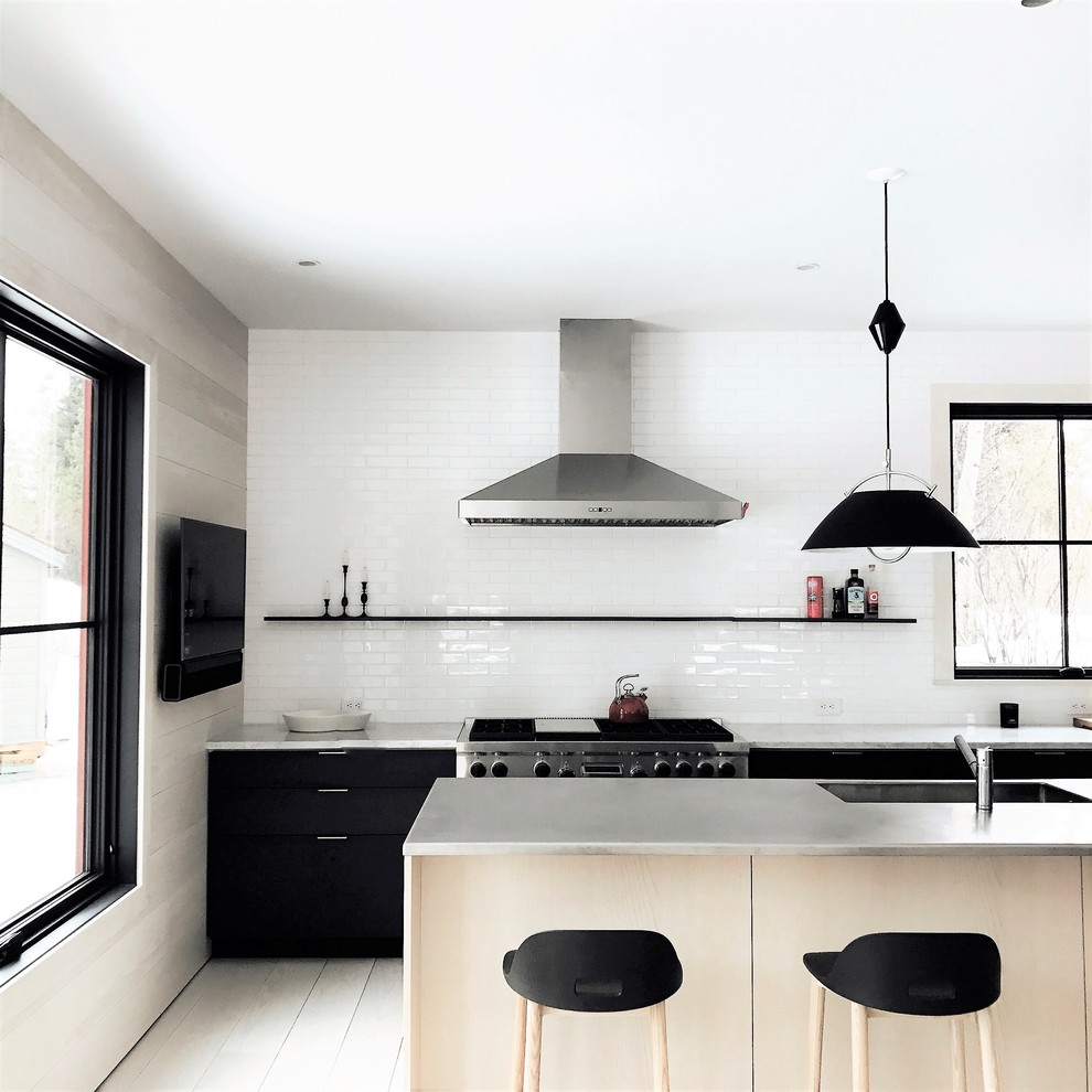 Design ideas for a mid-sized scandinavian u-shaped open plan kitchen in New York with flat-panel cabinets, white splashback, subway tile splashback, stainless steel appliances, light hardwood floors, with island and a single-bowl sink.