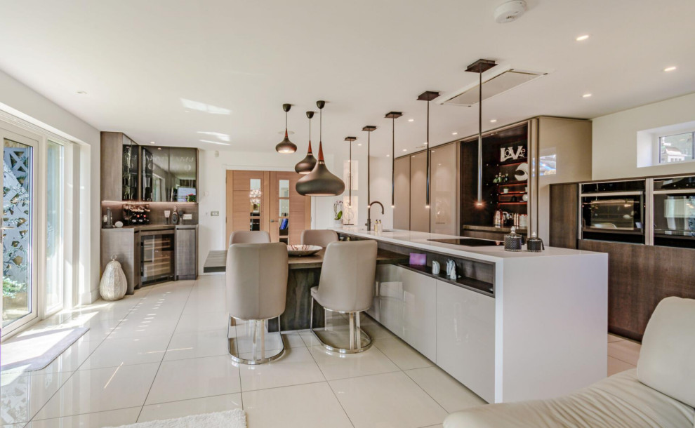 Large contemporary galley kitchen in Manchester with an undermount sink, flat-panel cabinets, dark wood cabinets, quartzite benchtops, brown splashback, stainless steel appliances, porcelain floors, with island, beige floor and beige benchtop.
