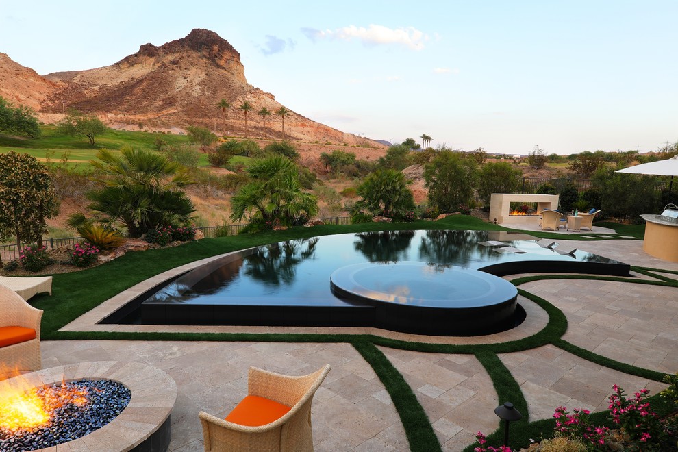 Photo of a contemporary backyard custom-shaped infinity pool in Las Vegas with a hot tub and natural stone pavers.