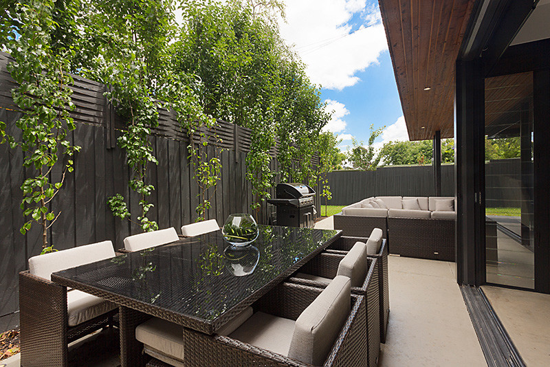 This is an example of a large contemporary side yard patio in Other with concrete slab and a roof extension.