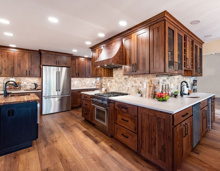 Design ideas for a large eat-in kitchen in Denver with dark wood cabinets, stainless steel appliances, brown floor, white benchtop, a farmhouse sink, travertine splashback, with island, recessed-panel cabinets, multi-coloured splashback, dark hardwood floors and quartzite benchtops.