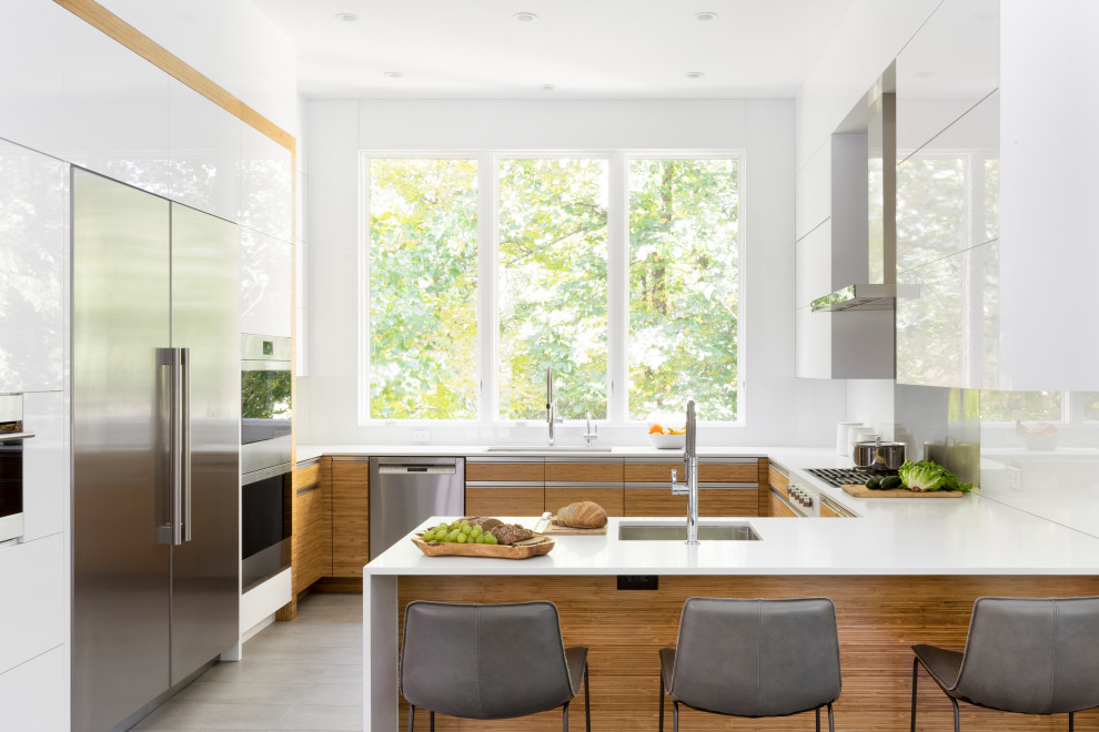 Inspiration for a large contemporary u-shaped kitchen/diner in New York with flat-panel cabinets, engineered stone countertops, white splashback, stone slab splashback, stainless steel appliances, porcelain flooring, a breakfast bar, grey floors, yellow worktops and medium wood cabinets.