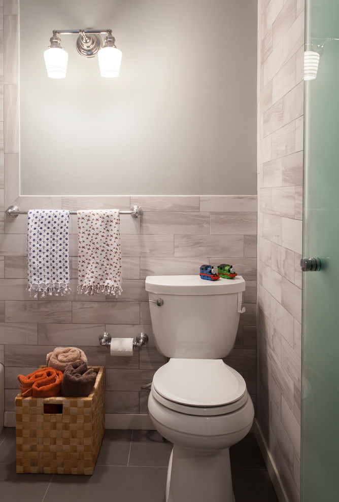 Small transitional kids' gray tile and porcelain tile ceramic tile and gray floor tub/shower combo photo with flat-panel cabinets, white cabinets, beige walls, marble countertops, a two-piece toilet and an undermount sink