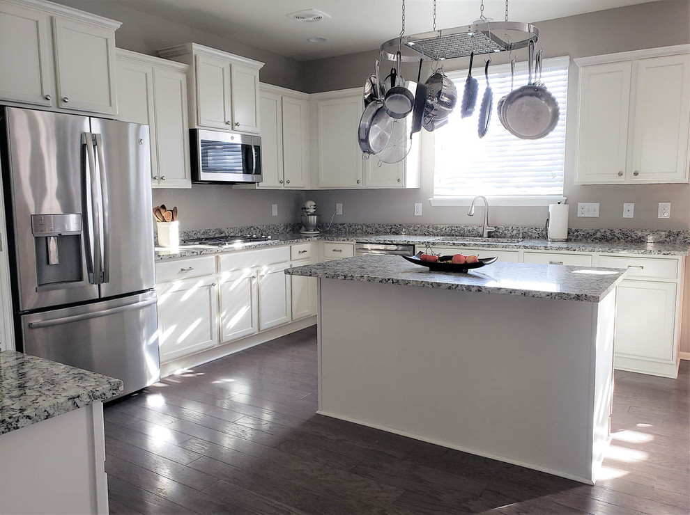 This is an example of a large traditional u-shaped kitchen in Denver with an undermount sink, recessed-panel cabinets, white cabinets, granite benchtops, stainless steel appliances, dark hardwood floors, with island, blue floor and multi-coloured benchtop.