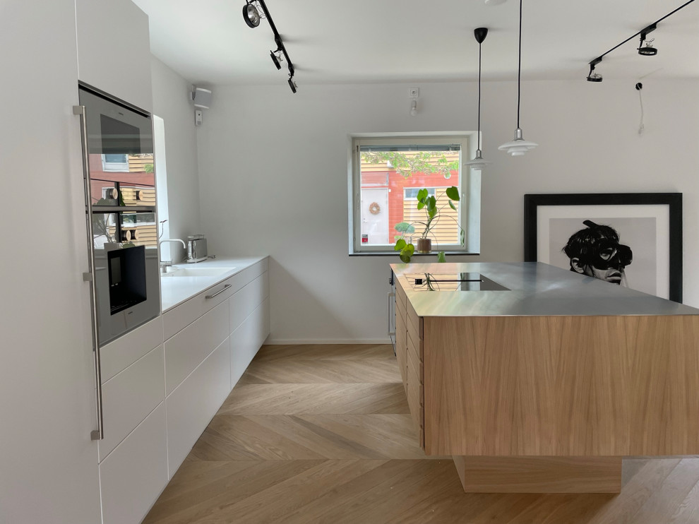 Minimalistisk inredning av ett mellanstort vit linjärt vitt kök och matrum, med en enkel diskho, släta luckor, vita skåp, bänkskiva i koppar, integrerade vitvaror, ljust trägolv och en köksö