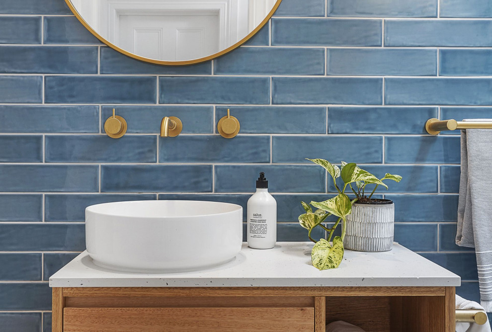 Small transitional powder room in Melbourne with flat-panel cabinets, medium wood cabinets, a one-piece toilet, blue tile, ceramic tile, grey walls, porcelain floors, a vessel sink, terrazzo benchtops, grey floor, grey benchtops and a floating vanity.
