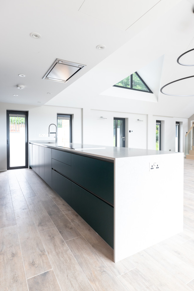 Immagine di una cucina minimalista di medie dimensioni con ante verdi, top in quarzite, elettrodomestici neri, top bianco e pavimento marrone