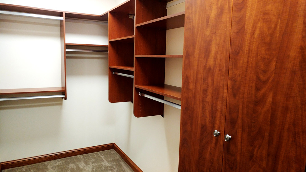 Inspiration for an expansive midcentury gender-neutral walk-in wardrobe in Milwaukee with flat-panel cabinets, medium wood cabinets, carpet and grey floor.