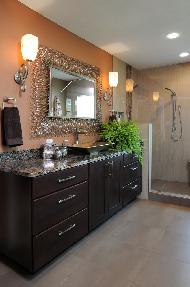 This is an example of a large transitional master bathroom in Cincinnati with shaker cabinets, dark wood cabinets, an alcove shower, a two-piece toilet, beige tile, porcelain tile, beige walls, porcelain floors, a vessel sink, granite benchtops, beige floor and a hinged shower door.