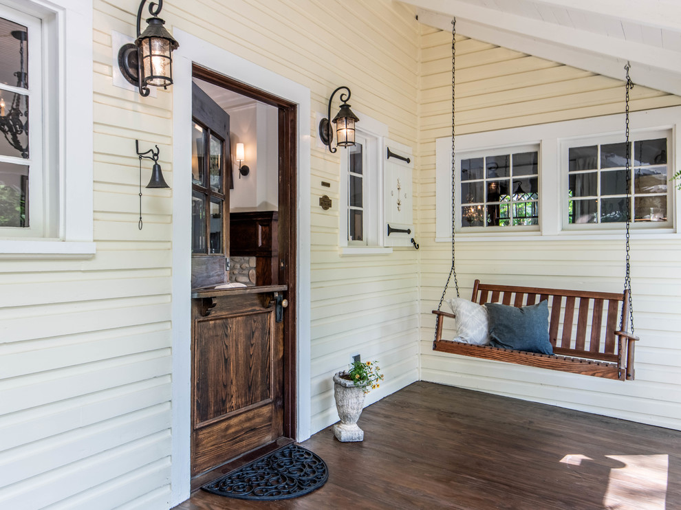 Design ideas for a mid-sized country front door in Other with yellow walls, dark hardwood floors, a dutch front door, a dark wood front door and brown floor.