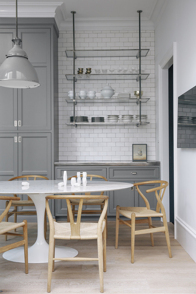 Inspiration for a scandinavian eat-in kitchen in San Francisco with recessed-panel cabinets, grey cabinets, white splashback, subway tile splashback and light hardwood floors.
