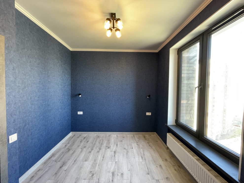 Immagine di una camera matrimoniale minimal di medie dimensioni con pareti blu, pavimento in laminato, pavimento beige e carta da parati