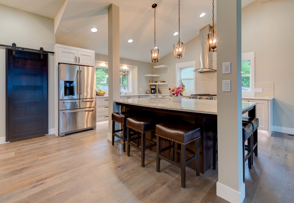 Inspiration for a mid-sized transitional l-shaped medium tone wood floor eat-in kitchen remodel in Vancouver with an undermount sink, shaker cabinets, white cabinets, quartz countertops, gray backsplash, glass tile backsplash, stainless steel appliances and an island