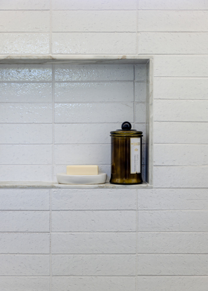Lantlig inredning av ett mycket stort vit vitt badrum med dusch, med luckor med upphöjd panel, blå skåp, en dusch i en alkov, en toalettstol med hel cisternkåpa, vit kakel, vita väggar, kalkstensgolv, ett nedsänkt handfat, marmorbänkskiva, grått golv och dusch med gångjärnsdörr