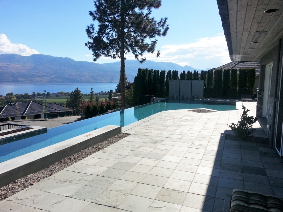 Photo of a large modern front yard l-shaped lap pool in Vancouver with tile.