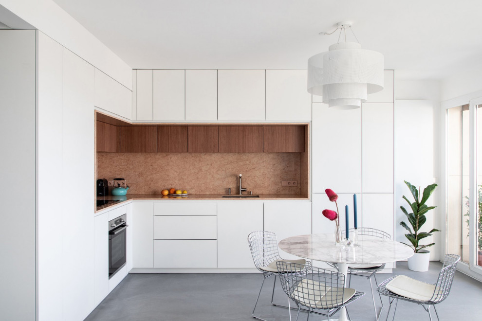 Photo of a mid-sized contemporary l-shaped eat-in kitchen in Paris with an integrated sink, beaded inset cabinets, white cabinets, marble benchtops, pink splashback, marble splashback, panelled appliances, concrete floors, grey floor, pink benchtop and no island.