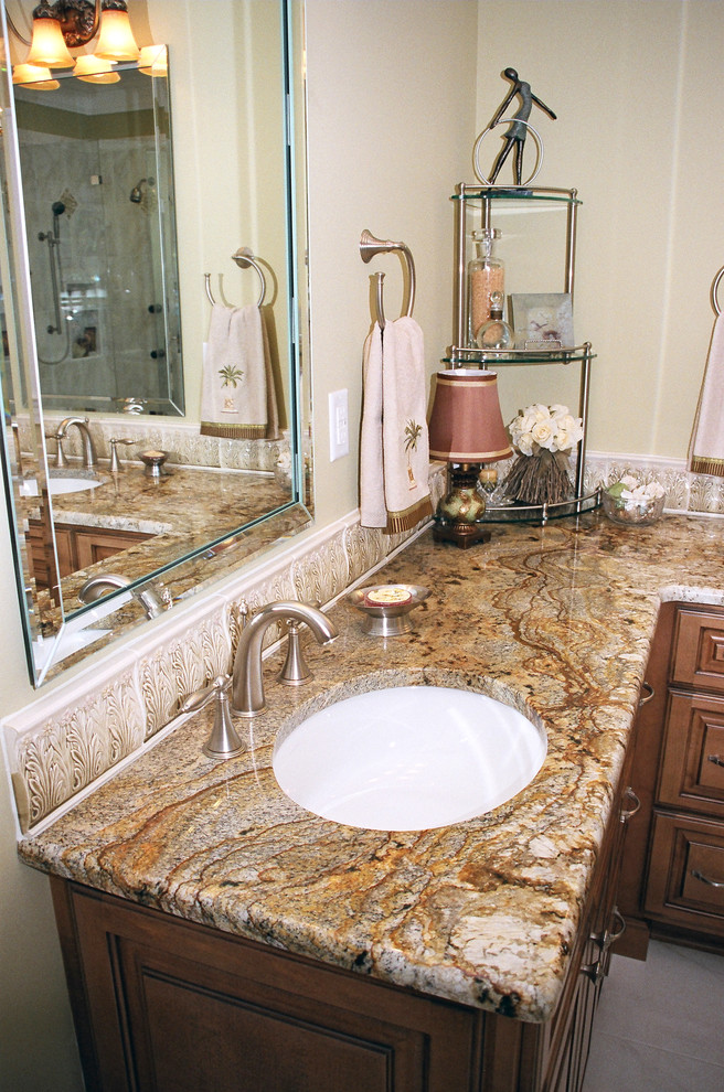 Inspiration for a large traditional master bathroom in Other with an undermount sink, raised-panel cabinets, medium wood cabinets, granite benchtops, a drop-in tub, a corner shower, a two-piece toilet, white tile, porcelain tile, yellow walls and porcelain floors.