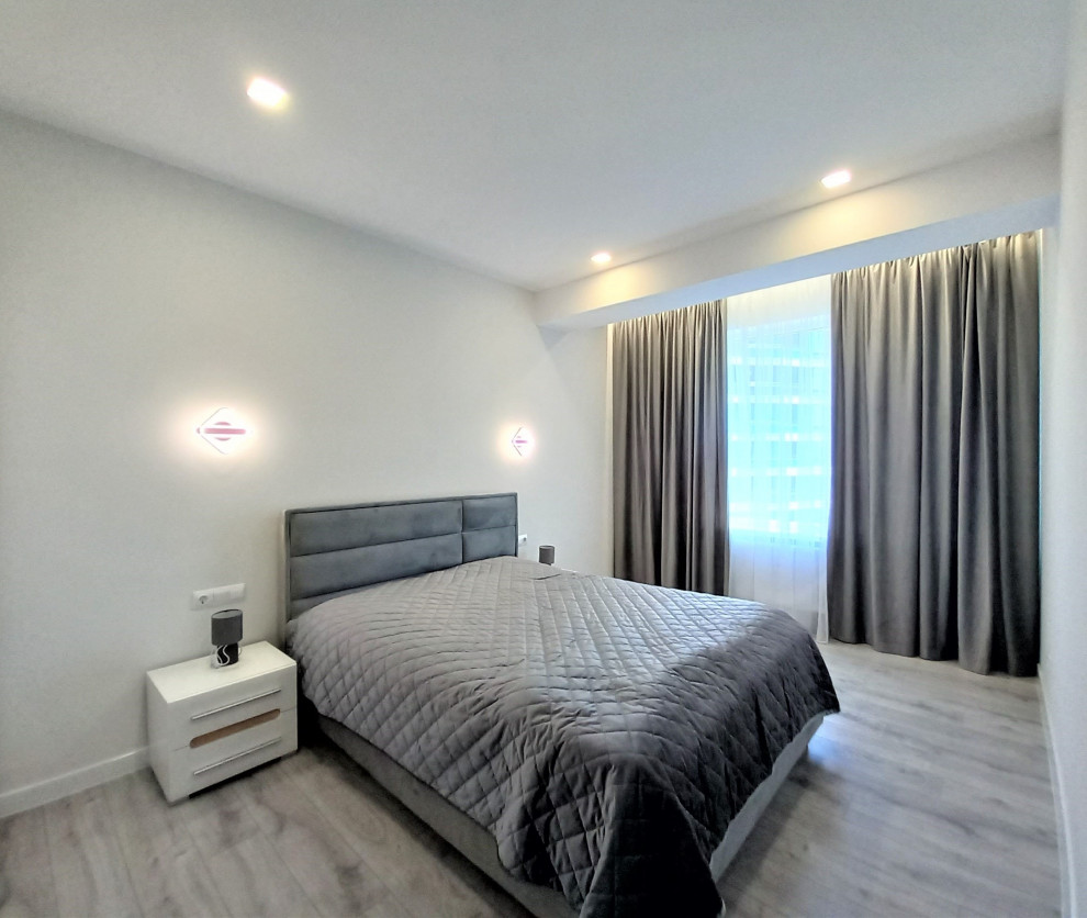 Идея дизайна: хозяйская, серо-белая спальня среднего размера, в светлых тонах в современном стиле с белыми стенами, полом из ламината, коричневым полом и обоями на стенах без камина