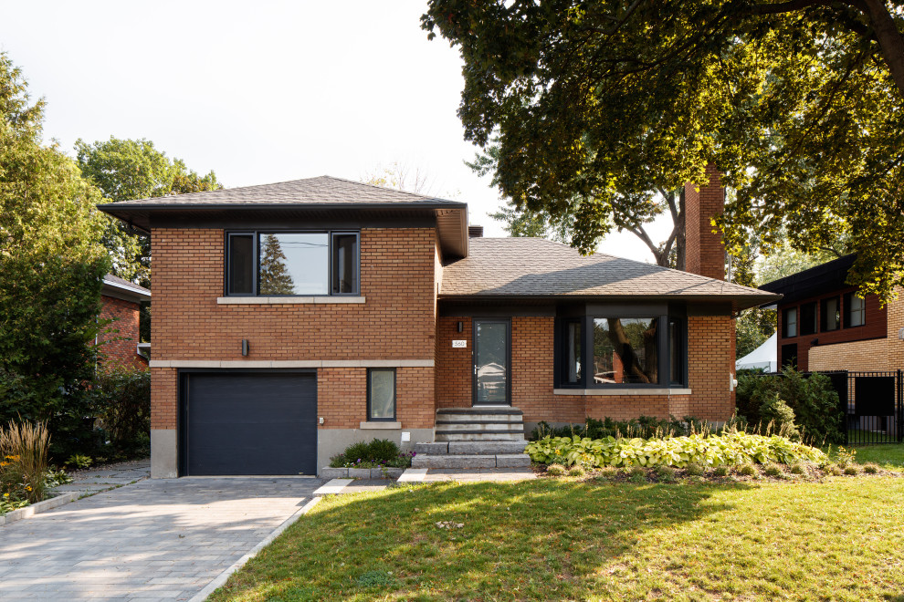 Small midcentury two-storey brick orange house exterior in Montreal with a gable roof, a shingle roof, a black roof and shingle siding.