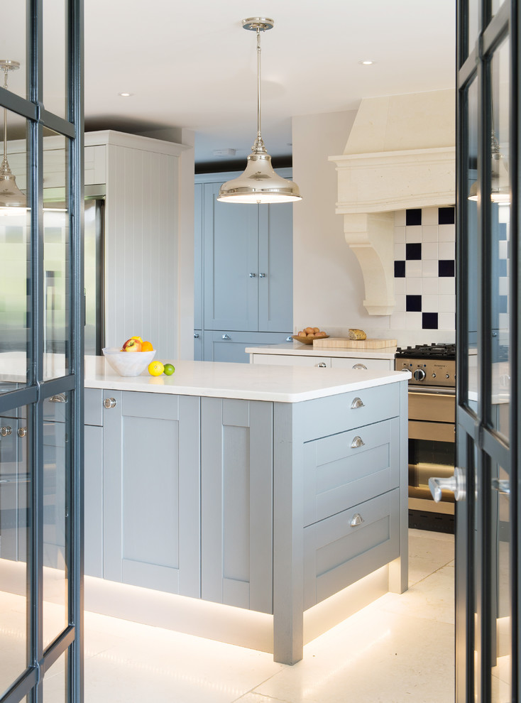 Design ideas for a mid-sized contemporary u-shaped open plan kitchen in Cornwall with a farmhouse sink, shaker cabinets, grey cabinets, quartzite benchtops, white splashback, ceramic splashback, stainless steel appliances, limestone floors, with island, beige floor and white benchtop.