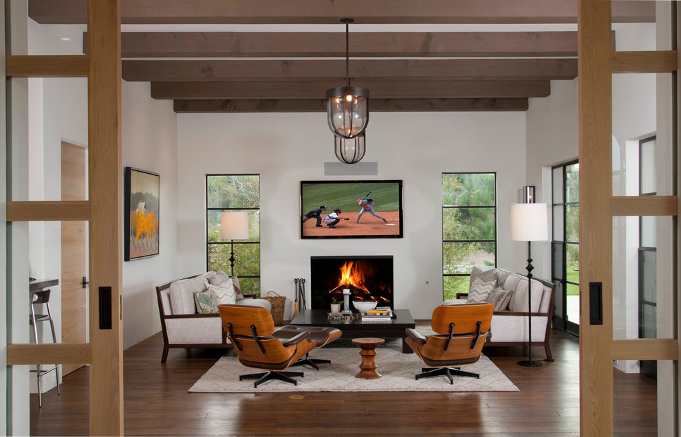 This is an example of a mediterranean enclosed family room in San Diego with a standard fireplace and a wall-mounted tv.