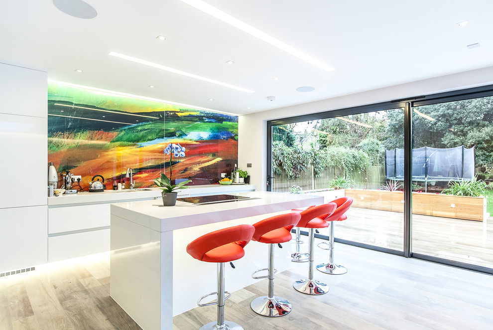 Photo of a contemporary eat-in kitchen in Surrey with an undermount sink, flat-panel cabinets, white cabinets, quartz benchtops, glass sheet splashback, porcelain floors, with island and multi-coloured splashback.