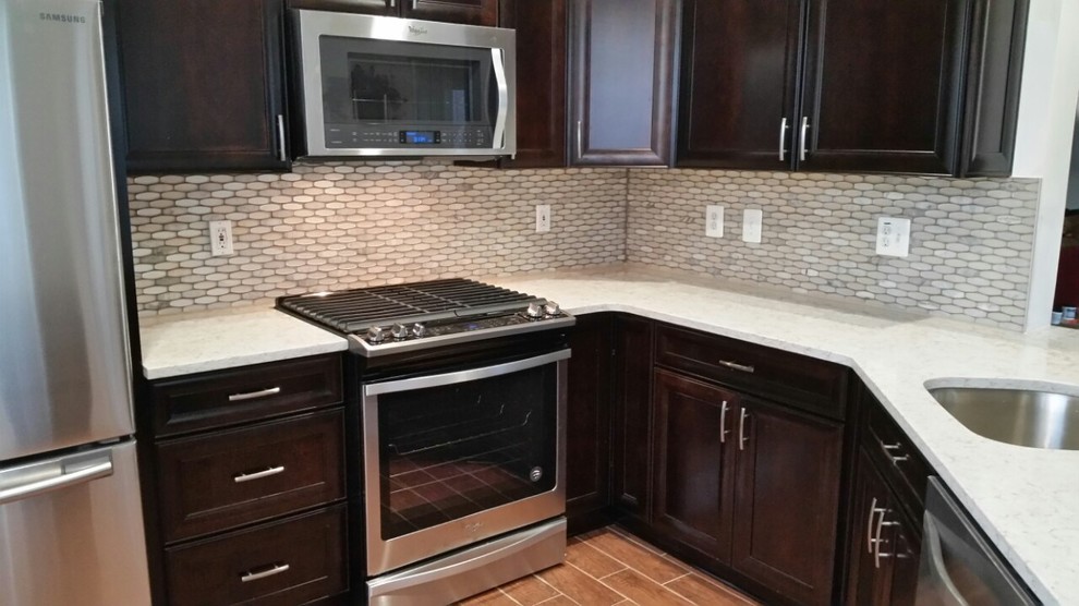 Inspiration for a mid-sized transitional l-shaped laminate floor and brown floor enclosed kitchen remodel in DC Metro with an undermount sink, recessed-panel cabinets, dark wood cabinets, quartzite countertops, white backsplash, mosaic tile backsplash, stainless steel appliances, a peninsula and white countertops