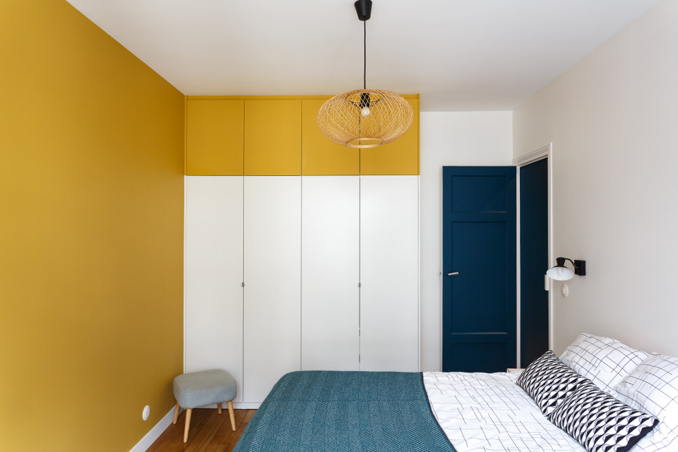 Photo of a mid-sized contemporary bedroom in Paris with yellow walls, light hardwood floors and brown floor.