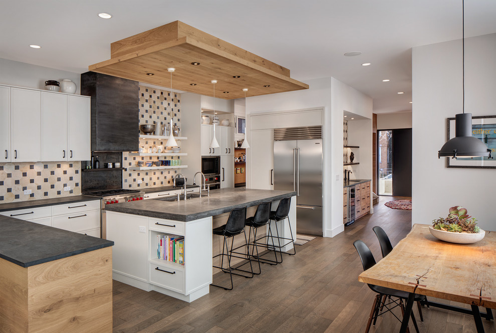 Inspiration for an expansive contemporary l-shaped open plan kitchen in Chicago with an undermount sink, recessed-panel cabinets, white cabinets, concrete benchtops, multi-coloured splashback, stone tile splashback, stainless steel appliances, medium hardwood floors and multiple islands.