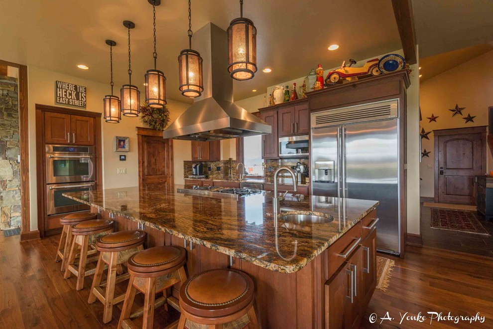 Example of a mid-sized mountain style l-shaped dark wood floor open concept kitchen design with an undermount sink, shaker cabinets, dark wood cabinets, granite countertops, multicolored backsplash, stone slab backsplash, stainless steel appliances and an island