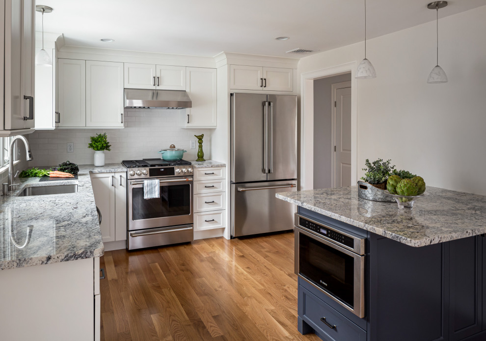 Design ideas for a mid-sized transitional l-shaped kitchen in Boston with an undermount sink, granite benchtops, white splashback, subway tile splashback, stainless steel appliances, brown floor, recessed-panel cabinets, white cabinets, medium hardwood floors, a peninsula and grey benchtop.