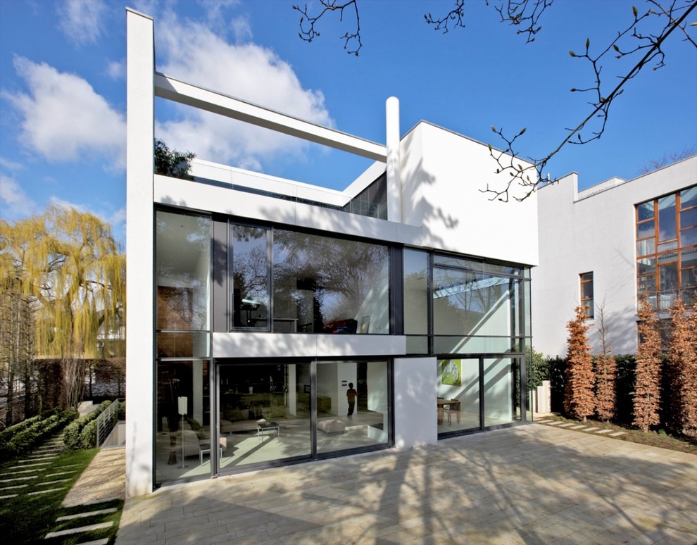 This is an example of a mid-sized contemporary three-storey white exterior in Dortmund with a flat roof.