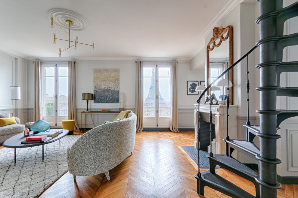 パリにあるお手頃価格の広いトランジショナルスタイルのおしゃれなリビング (白い壁、淡色無垢フローリング、暖炉なし、テレビなし、ベージュの床、パネル壁) の写真
