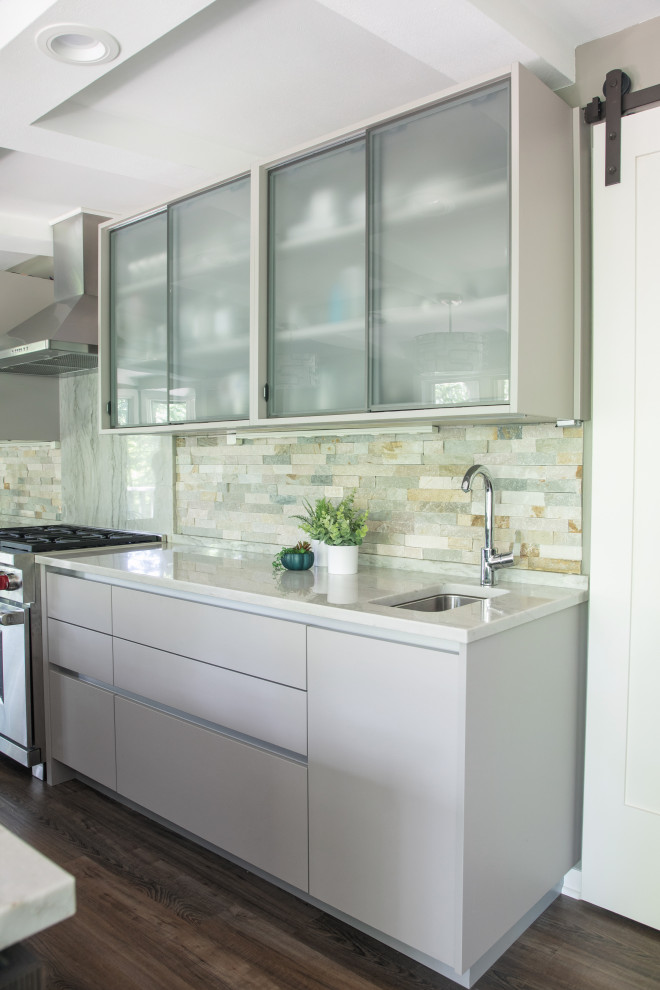 Photo of a medium sized contemporary galley enclosed kitchen in Other with a single-bowl sink, flat-panel cabinets, grey cabinets, stone tiled splashback, stainless steel appliances, laminate floors, an island, brown floors and grey worktops.