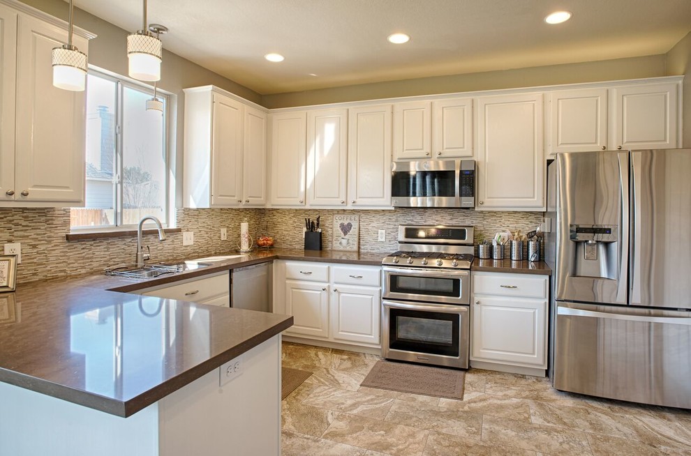 Eat-in kitchen - large transitional u-shaped eat-in kitchen idea in Austin with raised-panel cabinets, white cabinets, beige backsplash, matchstick tile backsplash, stainless steel appliances and a peninsula
