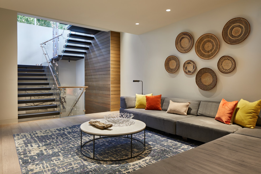 Photo of an expansive modern open concept family room in Seattle with white walls, light hardwood floors, a wall-mounted tv and brown floor.