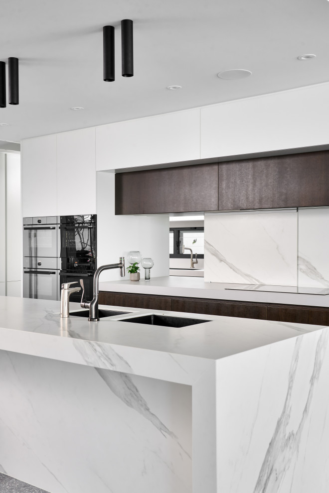 Eat-in kitchen - huge contemporary l-shaped concrete floor and gray floor eat-in kitchen idea in Perth with an undermount sink, flat-panel cabinets, white cabinets, quartz countertops, white backsplash, porcelain backsplash, black appliances, an island and white countertops