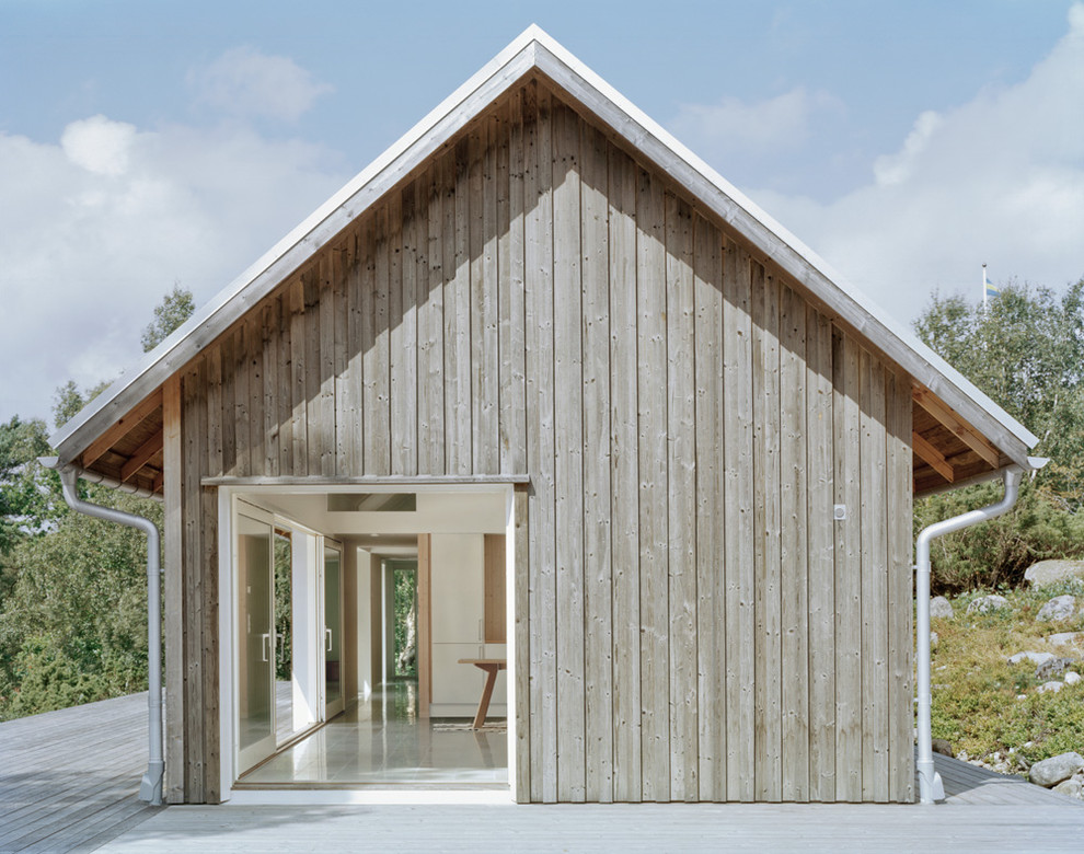 Bild på ett mellanstort minimalistiskt grått trähus, med allt i ett plan och halvvalmat sadeltak