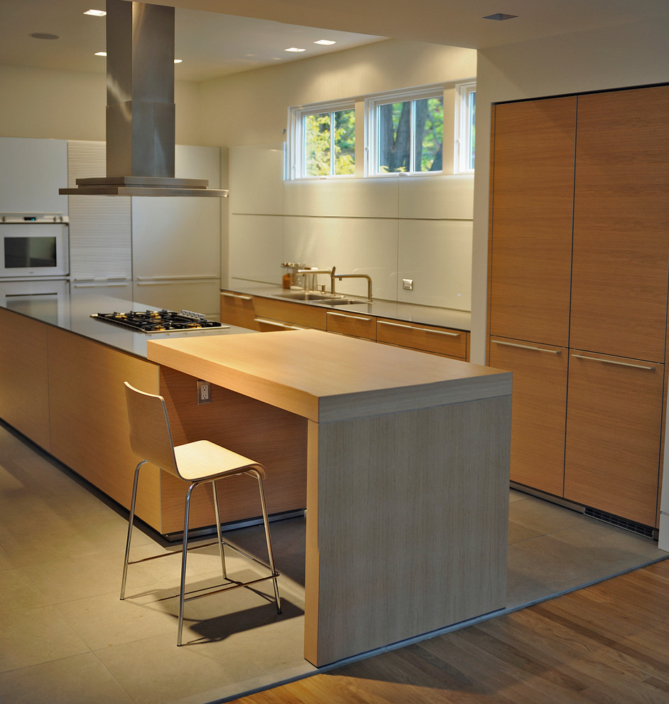 Large modern u-shaped eat-in kitchen in DC Metro with a double-bowl sink, flat-panel cabinets, light wood cabinets, grey splashback, glass sheet splashback, stainless steel appliances, concrete floors, with island and wood benchtops.