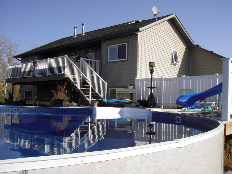 Large backyard round aboveground pool in Other with decking.