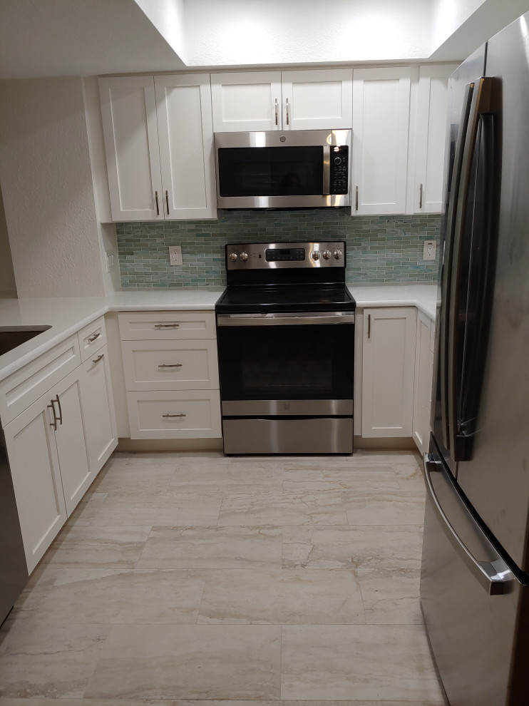 Example of a small beach style u-shaped porcelain tile and beige floor eat-in kitchen design in Tampa with an undermount sink, shaker cabinets, white cabinets, quartz countertops, green backsplash, glass tile backsplash, stainless steel appliances, no island and white countertops