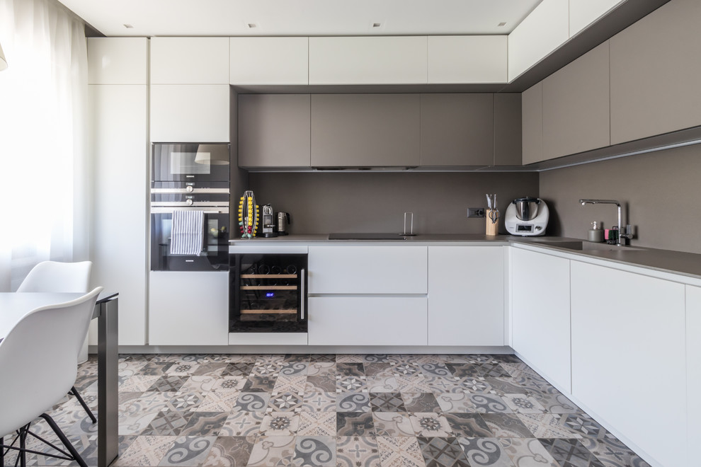 Inspiration for a large modern l-shaped separate kitchen in Other with a drop-in sink, flat-panel cabinets, white cabinets, tile benchtops, grey splashback, porcelain splashback, stainless steel appliances, ceramic floors, no island, brown floor and grey benchtop.