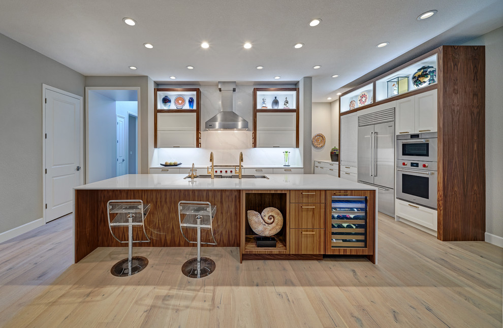 Mid-sized beach style l-shaped open plan kitchen in Sacramento with an undermount sink, quartz benchtops, white splashback, stone slab splashback, stainless steel appliances, light hardwood floors, with island, beige floor, white benchtop, recessed-panel cabinets and white cabinets.
