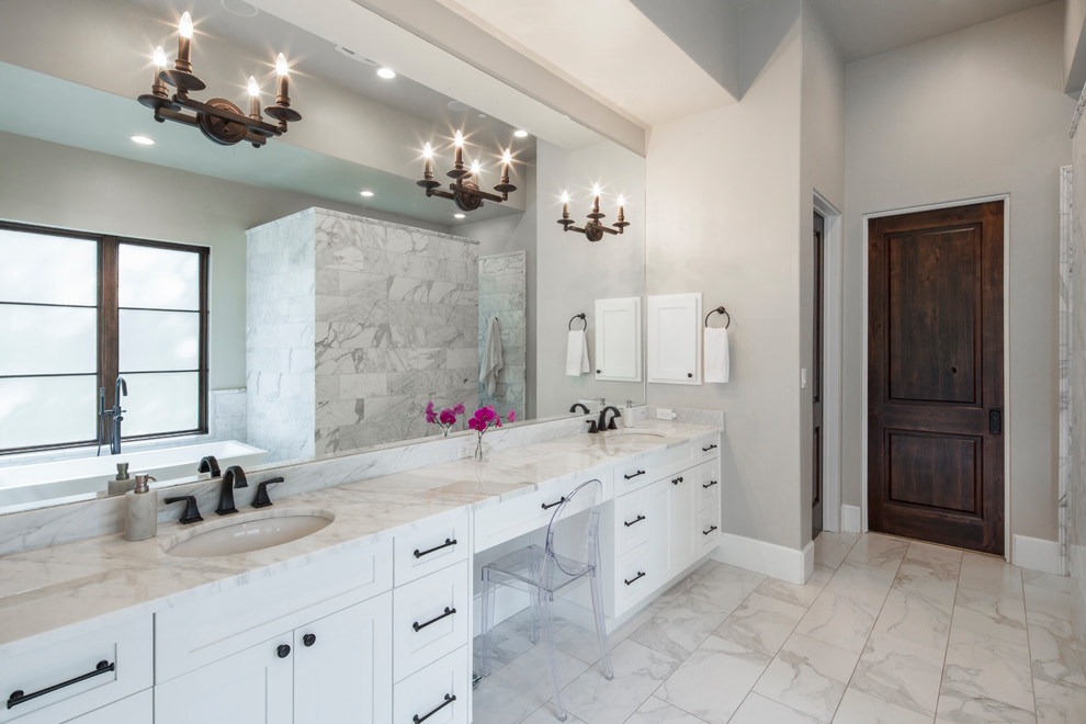 Photo of a large mediterranean master bathroom in Austin with shaker cabinets, white cabinets, a freestanding tub, an alcove shower, white tile, marble, beige walls, marble floors, an undermount sink, marble benchtops, white floor and an open shower.