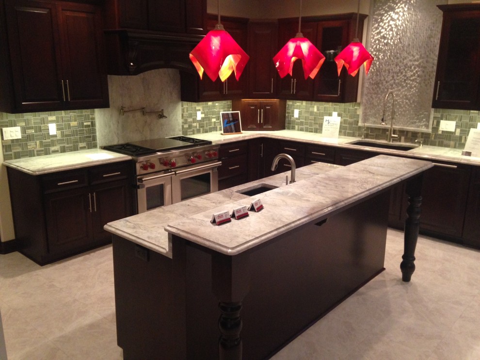 Elegant eat-in kitchen photo with recessed-panel cabinets, dark wood cabinets, granite countertops, gray backsplash, glass tile backsplash, stainless steel appliances and an island