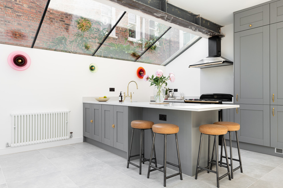Стильный дизайн: кухня в стиле лофт с обеденным столом, серыми фасадами, полуостровом, серым полом и белой столешницей - последний тренд